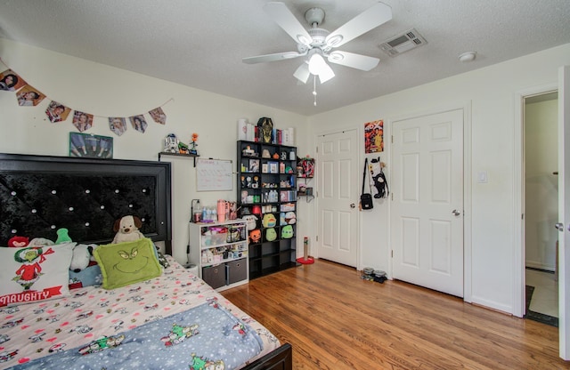 bedroom with ceiling fan, wood-type flooring, and a textured ceiling