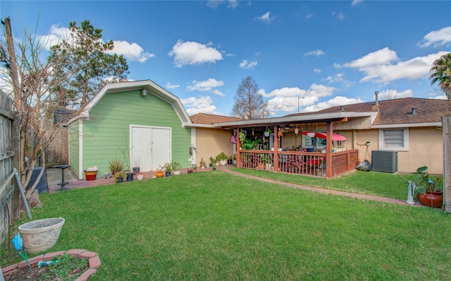 rear view of house featuring a yard, an outdoor structure, and central air condition unit