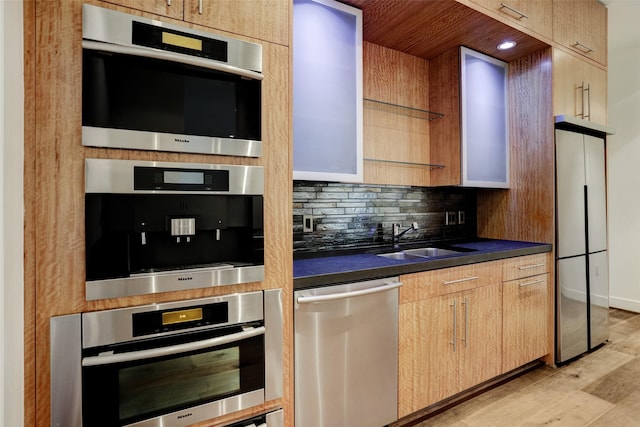 kitchen with sink, light hardwood / wood-style flooring, light brown cabinets, stainless steel appliances, and decorative backsplash