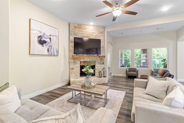 living room featuring ceiling fan, dark hardwood / wood-style floors, and a fireplace