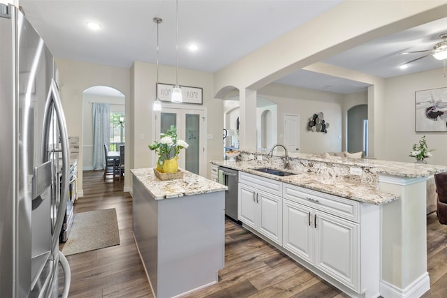 kitchen featuring sink, white cabinetry, stainless steel appliances, a center island, and decorative light fixtures