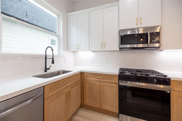 kitchen featuring tasteful backsplash, stainless steel appliances, sink, and white cabinets