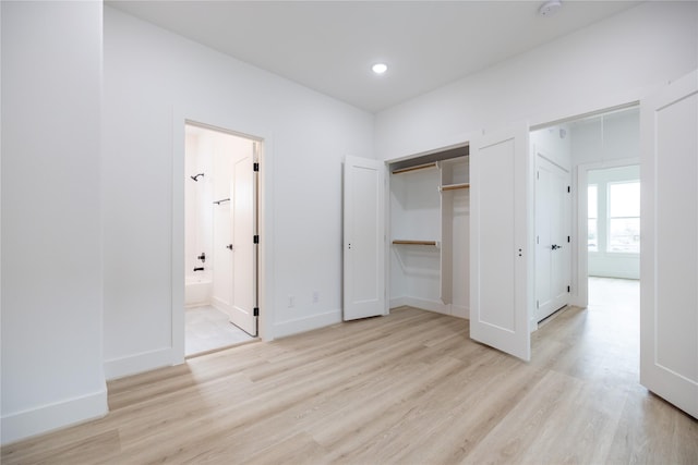 unfurnished bedroom featuring ensuite bath and light hardwood / wood-style floors