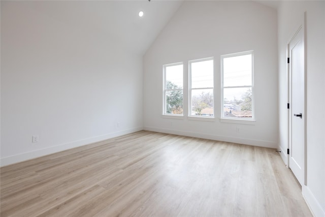 spare room with high vaulted ceiling and light hardwood / wood-style flooring