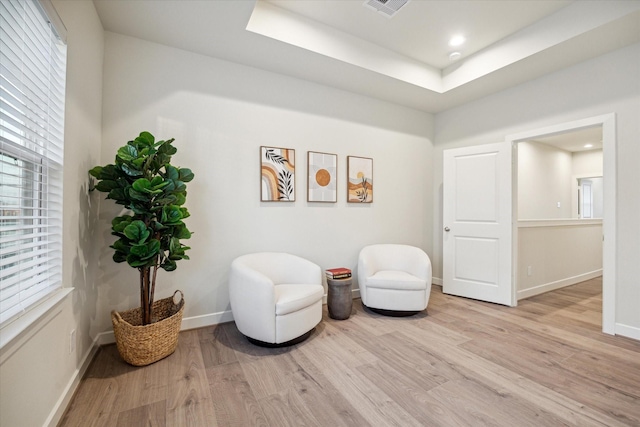 sitting room with a tray ceiling and light hardwood / wood-style flooring