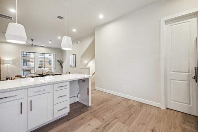 kitchen with hanging light fixtures, ceiling fan, white cabinets, and light wood-type flooring