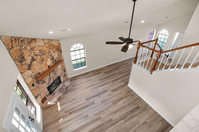 living room featuring hardwood / wood-style flooring, ceiling fan, a towering ceiling, and a fireplace