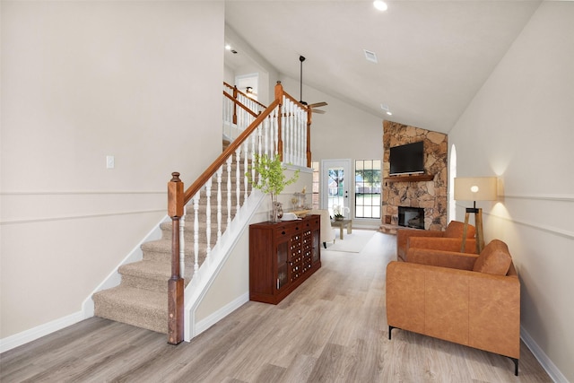 living room with a fireplace, high vaulted ceiling, ceiling fan, and light wood-type flooring