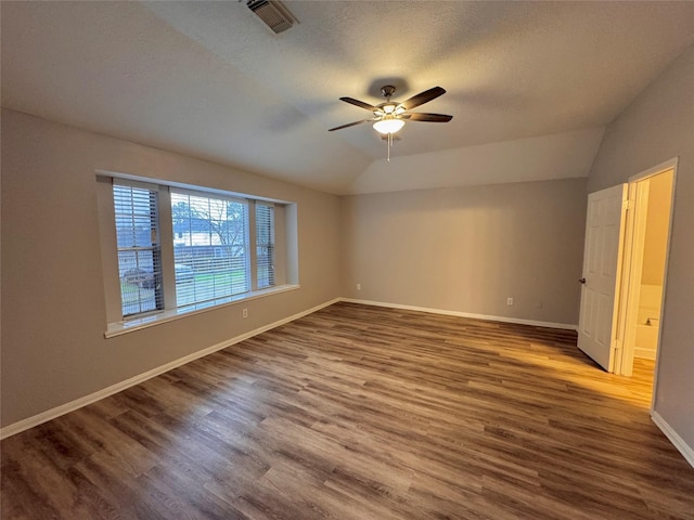 spare room with lofted ceiling, dark wood-type flooring, a textured ceiling, and ceiling fan