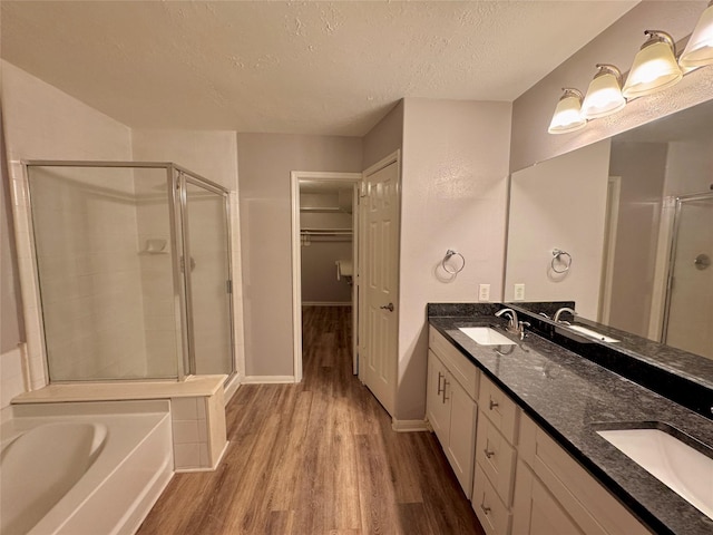 bathroom with vanity, a textured ceiling, wood-type flooring, and separate shower and tub