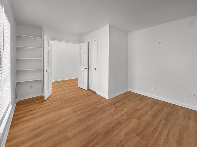 unfurnished bedroom featuring a closet, baseboards, and light wood finished floors