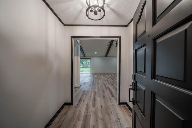 hall featuring crown molding, a textured ceiling, a notable chandelier, and light hardwood / wood-style floors