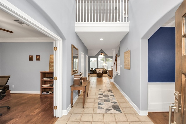 hallway with a towering ceiling and light hardwood / wood-style floors