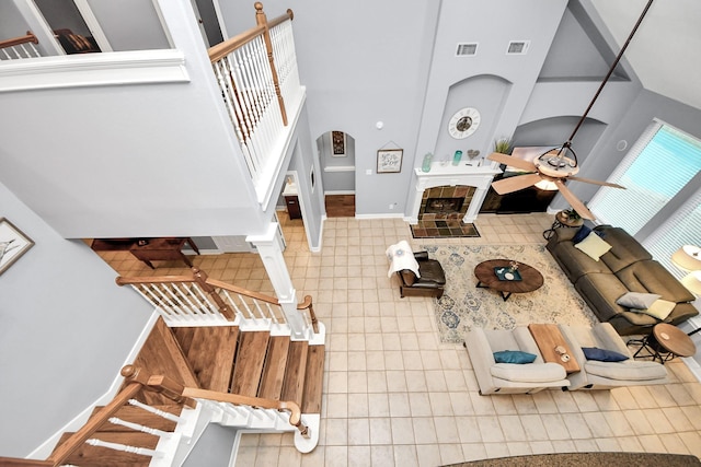 tiled living room with a tiled fireplace and ceiling fan