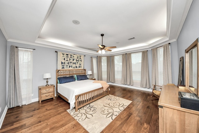 bedroom featuring crown molding, a tray ceiling, dark wood-type flooring, and ceiling fan