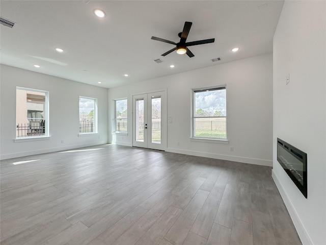 unfurnished living room featuring french doors, ceiling fan, and light hardwood / wood-style flooring