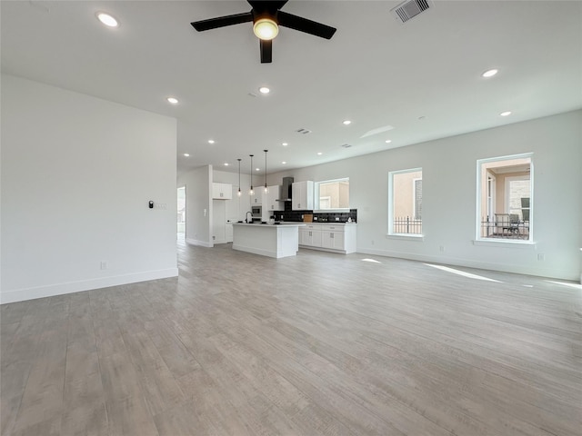 unfurnished living room featuring ceiling fan and light hardwood / wood-style flooring