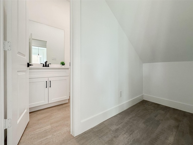 additional living space featuring vaulted ceiling, sink, and light hardwood / wood-style floors