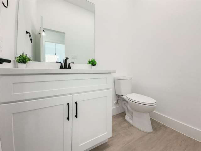 bathroom featuring wood-type flooring, toilet, and vanity