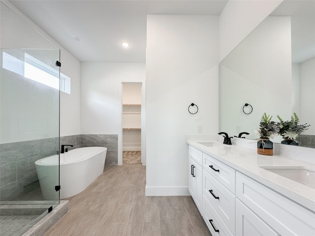 bathroom with vanity, independent shower and bath, hardwood / wood-style floors, and tile walls