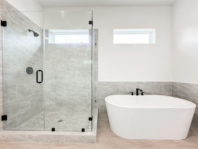 bathroom with tile walls, a wealth of natural light, and shower with separate bathtub