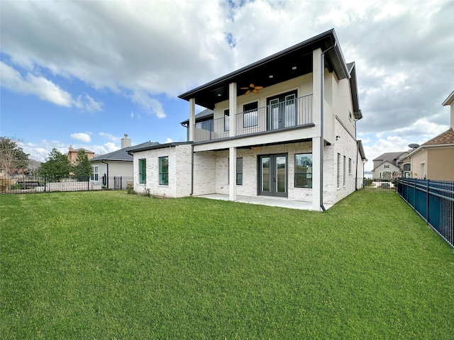 rear view of house featuring ceiling fan, a balcony, a patio, and a lawn