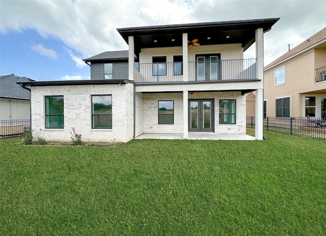 rear view of property featuring ceiling fan, a yard, a patio, french doors, and a balcony