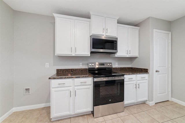 kitchen with stainless steel appliances, dark stone countertops, white cabinets, and light tile patterned floors