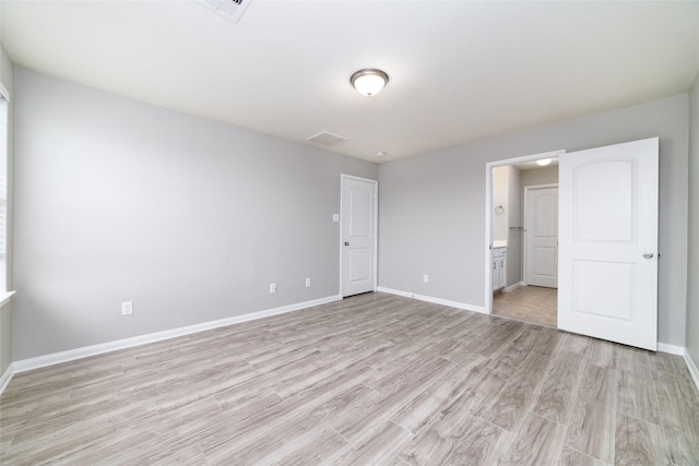 unfurnished bedroom featuring connected bathroom and light wood-type flooring