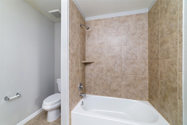 bathroom with tiled shower / bath, tile patterned floors, toilet, and a textured ceiling