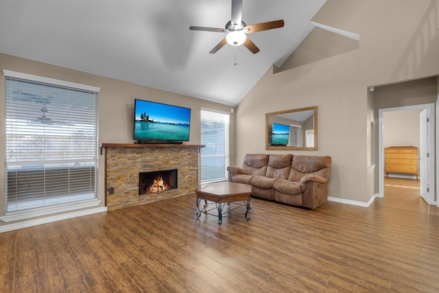 living room with hardwood / wood-style flooring, ceiling fan, a stone fireplace, and high vaulted ceiling