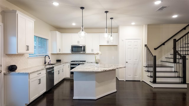 kitchen with white cabinetry, decorative light fixtures, a center island, and appliances with stainless steel finishes