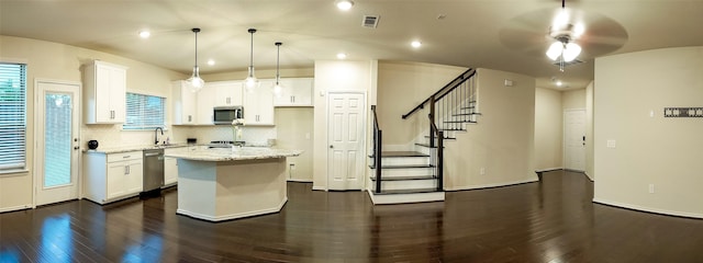 kitchen featuring white cabinetry, stainless steel appliances, hanging light fixtures, and a kitchen island