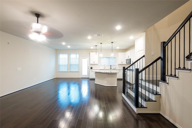 unfurnished living room with dark hardwood / wood-style floors and ceiling fan