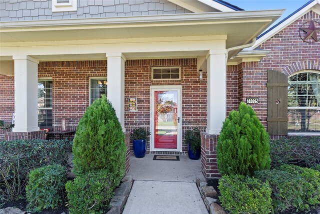 property entrance with brick siding and a porch