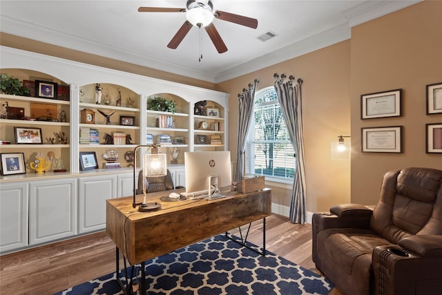 office featuring built in features, visible vents, a ceiling fan, wood finished floors, and crown molding