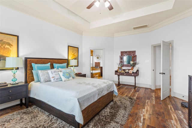 bedroom with dark wood-type flooring, visible vents, baseboards, ornamental molding, and a tray ceiling