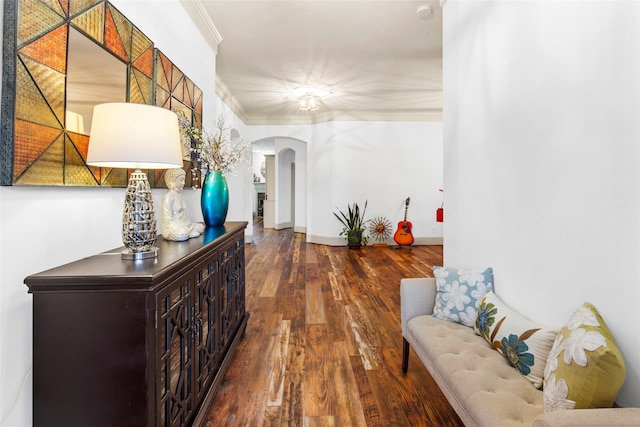 hallway with arched walkways, ornamental molding, dark wood-style floors, and baseboards