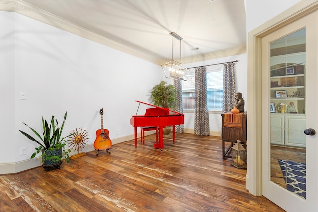 dining space with ornamental molding, a chandelier, baseboards, and wood finished floors