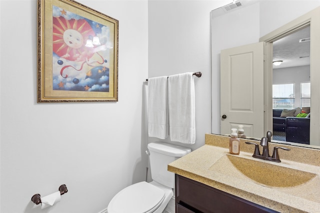 ensuite bathroom with toilet, vanity, visible vents, and connected bathroom