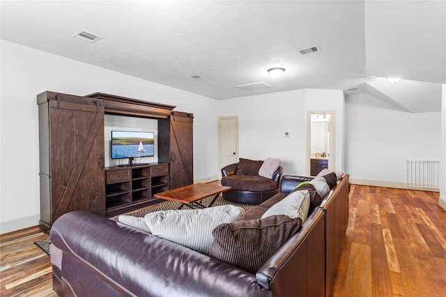 living area featuring wood finished floors, visible vents, and a barn door