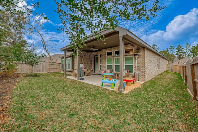 rear view of property featuring a yard, a patio, and ceiling fan