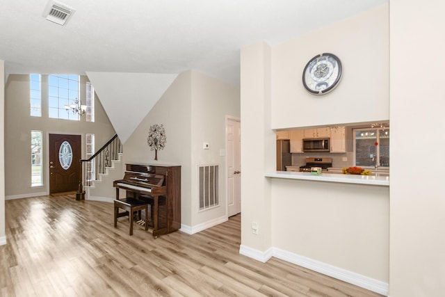 foyer entrance featuring an inviting chandelier, light hardwood / wood-style floors, and a high ceiling