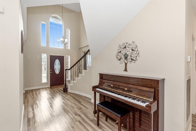 foyer featuring high vaulted ceiling, a chandelier, a wealth of natural light, and light wood-type flooring