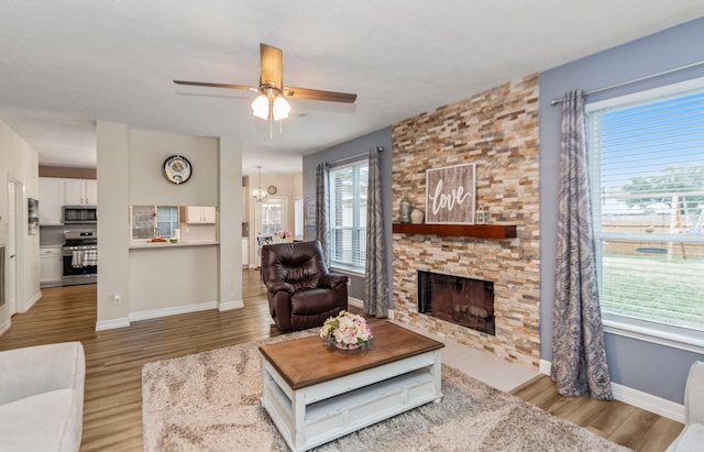 living room with hardwood / wood-style flooring, a fireplace, and ceiling fan with notable chandelier