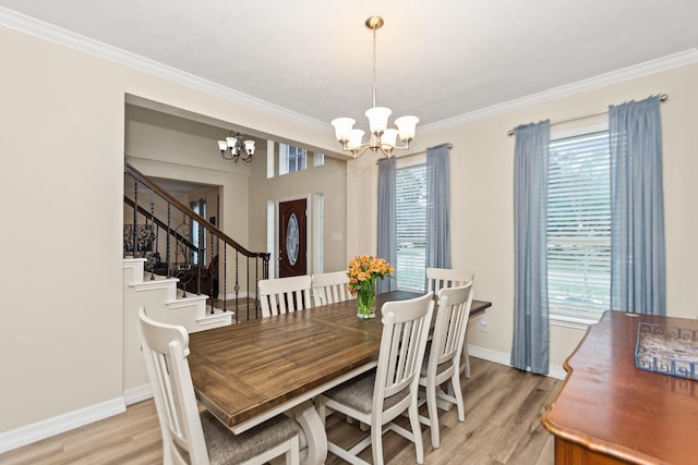 dining space with ornamental molding, plenty of natural light, light wood-type flooring, and a chandelier