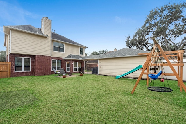 back of house with a yard and a playground