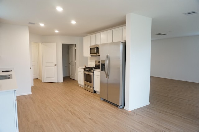 kitchen featuring stainless steel appliances, light wood-type flooring, and white cabinets