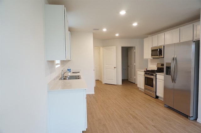 kitchen featuring sink, stainless steel appliances, white cabinets, and light wood-type flooring