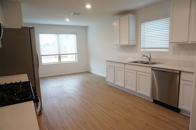 kitchen featuring dishwasher, sink, white cabinets, and light wood-type flooring